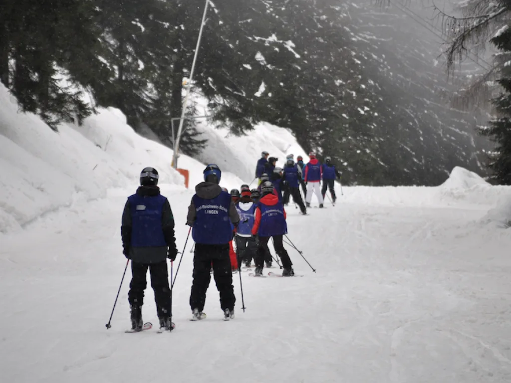 Skigruppe geht über einen schmalen Verbindungsweg.